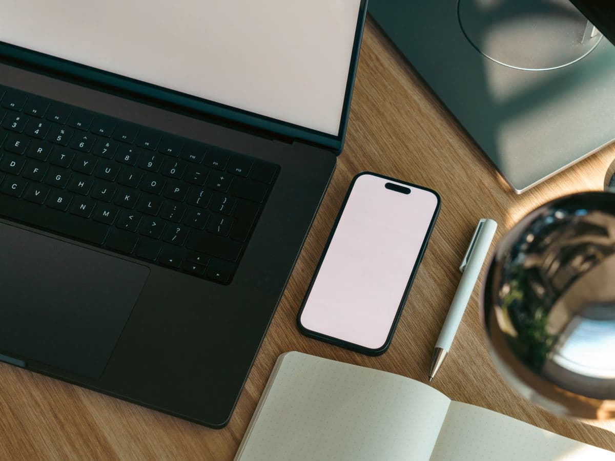 A tidy founder workspace — laptop, notebook and phone